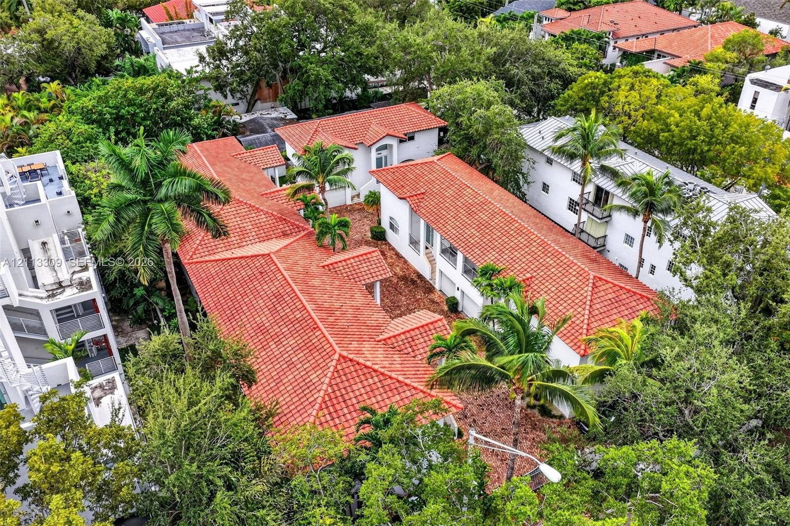 3082 Bird Avenue, #6, Miami, FL 33133 Aerial perspective of a multi-structure property featuring red clay tile roofing, white stucco exteriors, and established mature landscaping