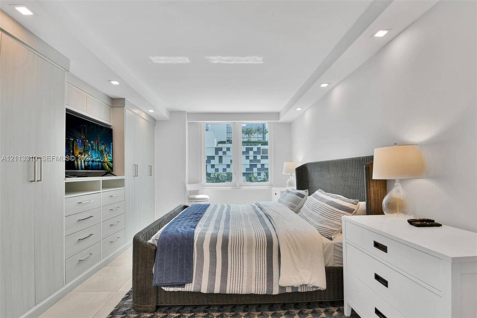 Built-in custom cabinetry with integrated shelving, recessed ceiling lighting, tray ceiling detail, large-format tile flooring, and oversized windows