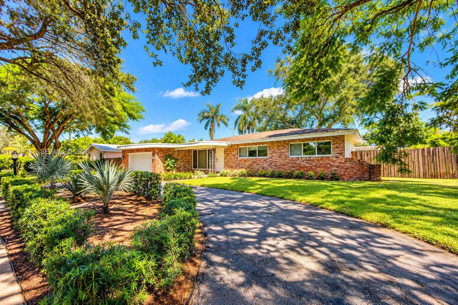 152 SW 59th Avenue, Plantation, Plantation, FL 33317 Ranch-style exterior featuring a multi-tonal brick faade, an attached single-car garage, an expansive manicured lawn, established landscaping, and a curved driveway