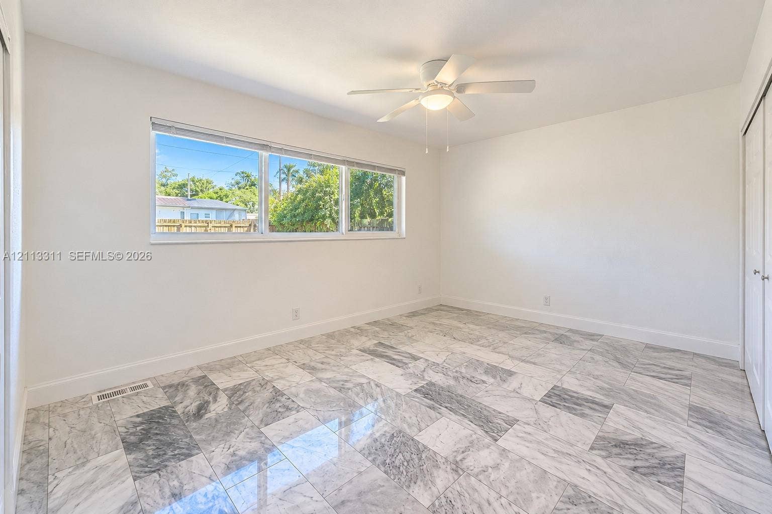 152 SW 59th Avenue, Plantation, Plantation, FL 33317 Room featuring polished stone tile flooring, a horizontal multi-pane window, and a ceiling-mounted light fixture with a central fan