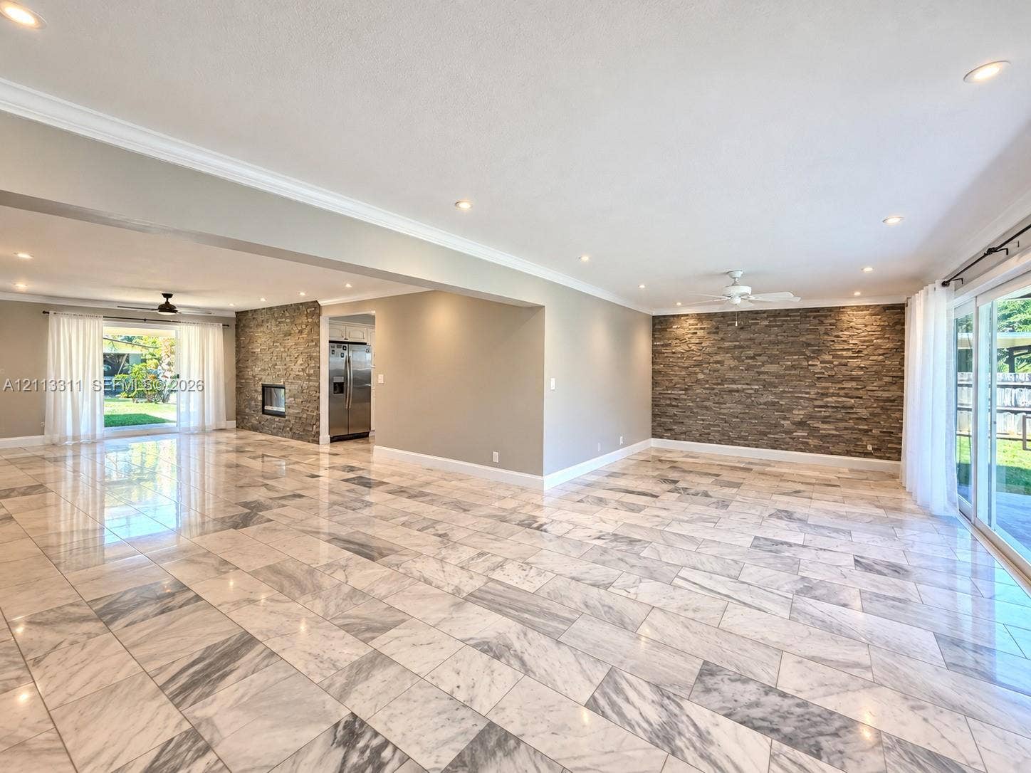 152 SW 59th Avenue, Plantation, Plantation, FL 33317 Spacious living area featuring polished stone flooring, stacked stone accent walls, recessed lighting, and multiple sliding glass doors