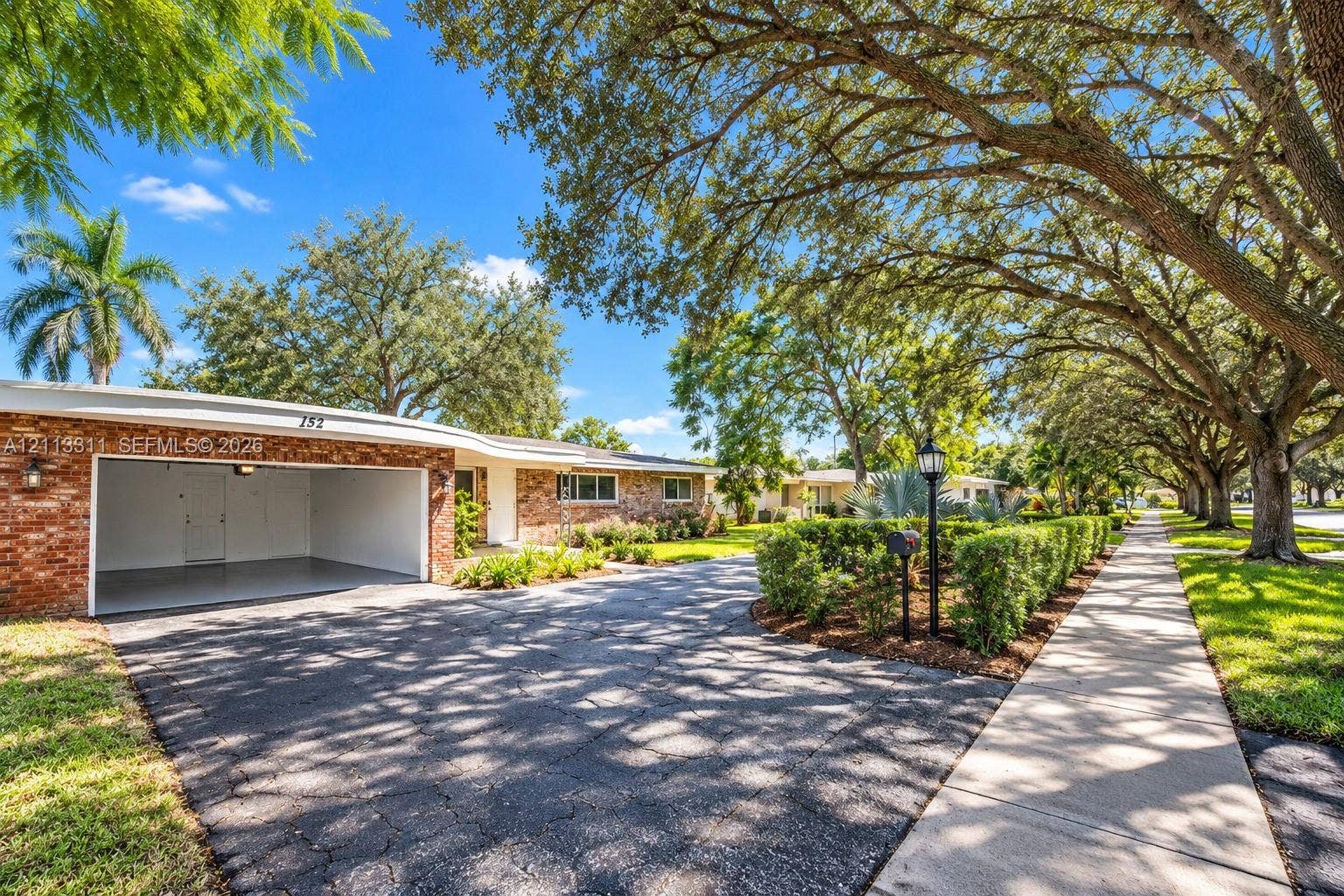 152 SW 59th Avenue, Plantation, Plantation, FL 33317 Exterior featuring a brick facade, integrated garage, paved driveway, and mature landscaping
