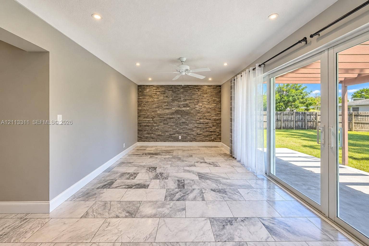 152 SW 59th Avenue, Plantation, Plantation, FL 33317 Interior space featuring large-format tile flooring, a stone-veneer accent wall, recessed lighting, and sliding glass doors opening to a covered patio