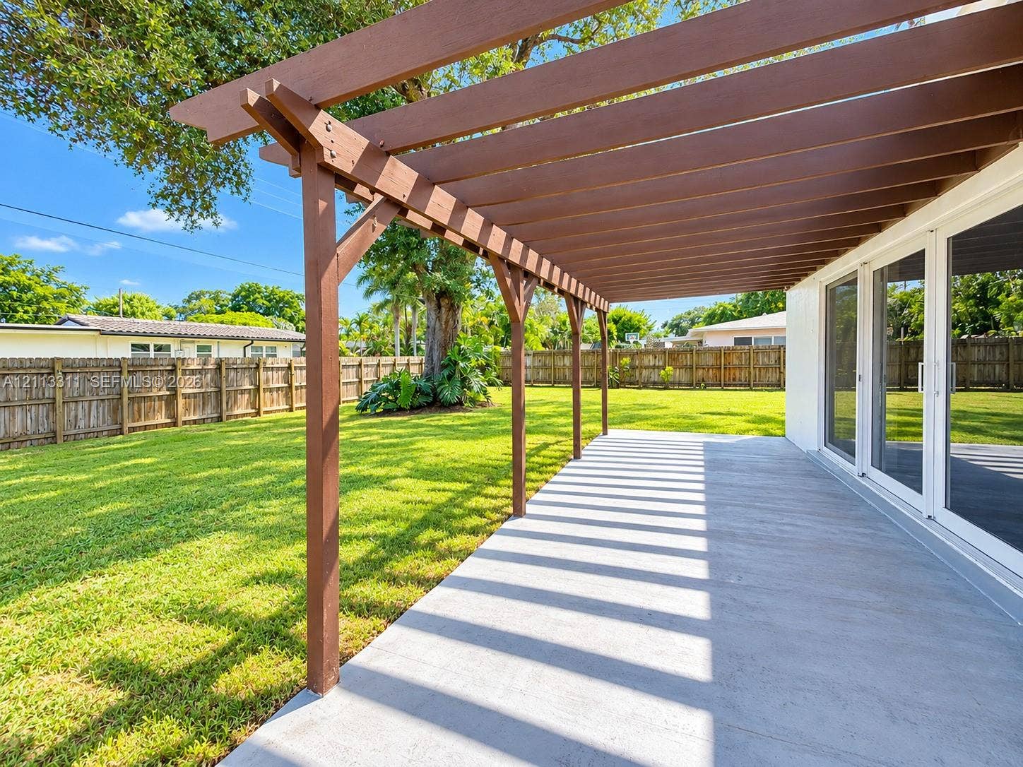 152 SW 59th Avenue, Plantation, Plantation, FL 33317 Covered patio featuring a timber-frame pergola, concrete flooring, sliding glass door entry, and a fenced backyard with mature landscaping