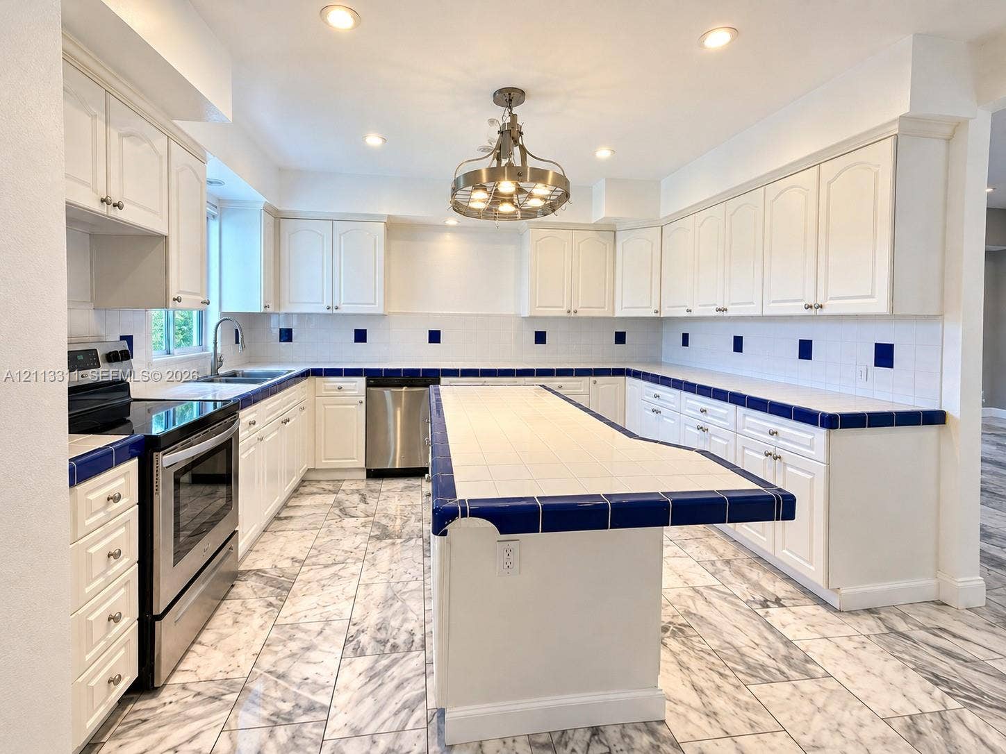 152 SW 59th Avenue, Plantation, Plantation, FL 33317 Kitchen featuring white cabinetry, an expansive central island, tile countertops with contrasting trim, stainless steel appliances, and stone-finish flooring