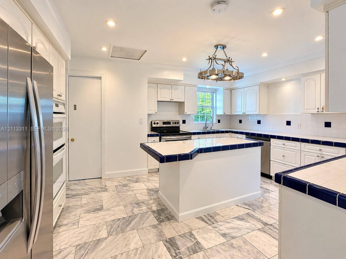 152 SW 59th Avenue, Plantation, Plantation, FL 33317 Kitchen featuring stone-tile flooring, white cabinetry, a center island with tiled countertops, stainless steel appliances, and a decorative overhead light fixture