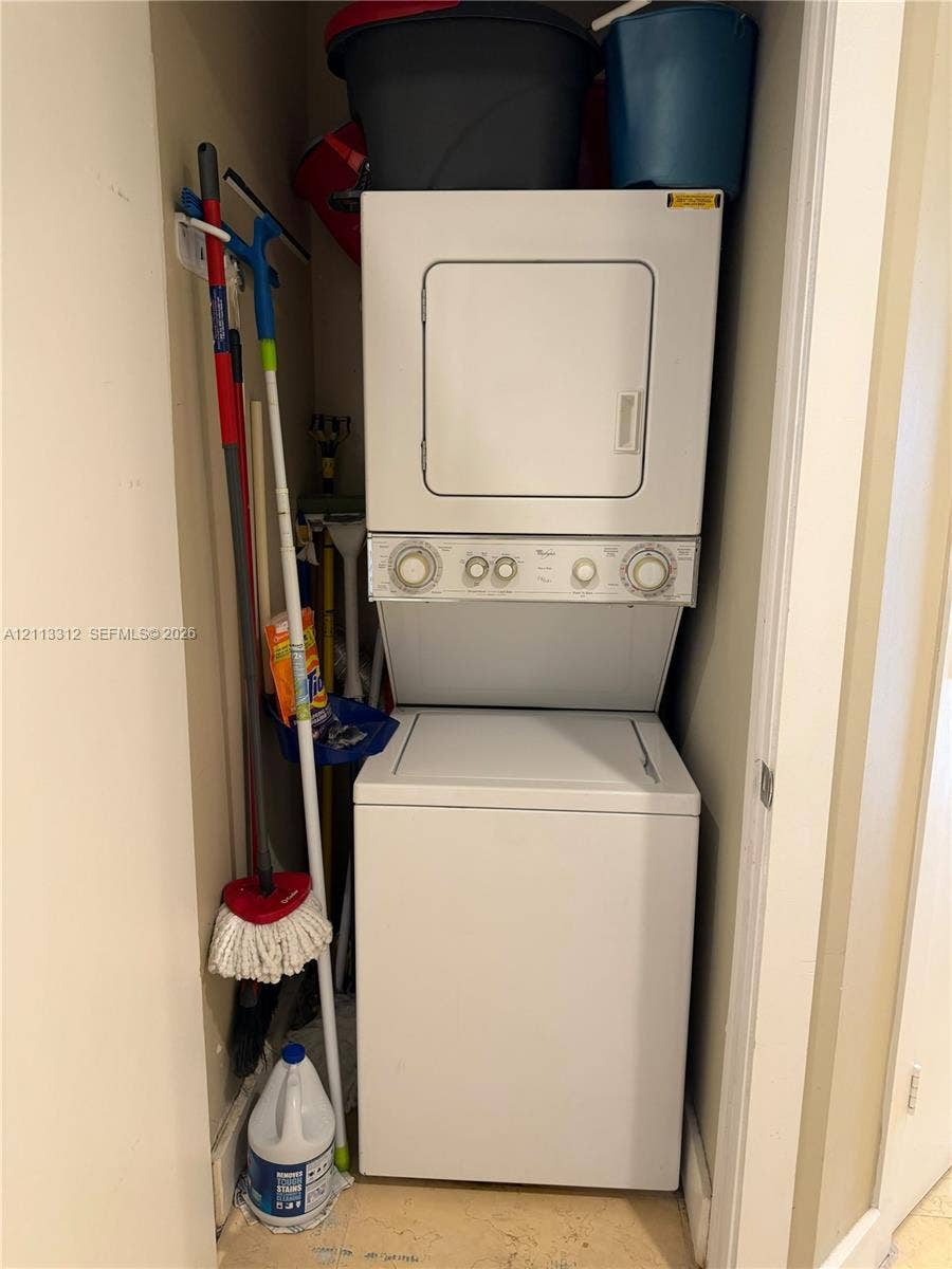 Stacked white washer and dryer unit housed within a dedicated laundry closet