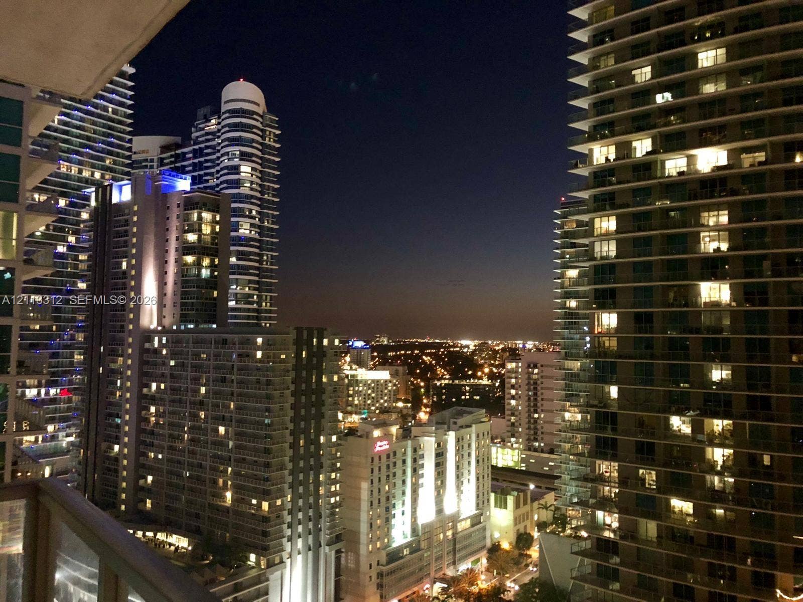 High-rise balcony featuring a metal railing and an expansive urban cityscape backdrop