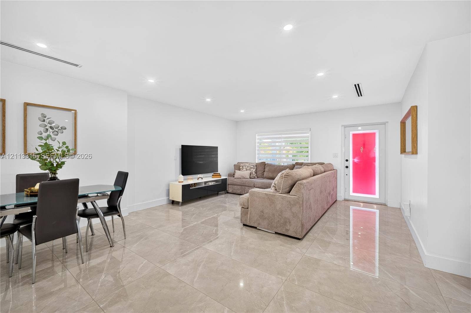 Open floor plan featuring large-format stone-finish tile flooring, recessed ceiling lighting, and a front entry door with integrated glass sidelights