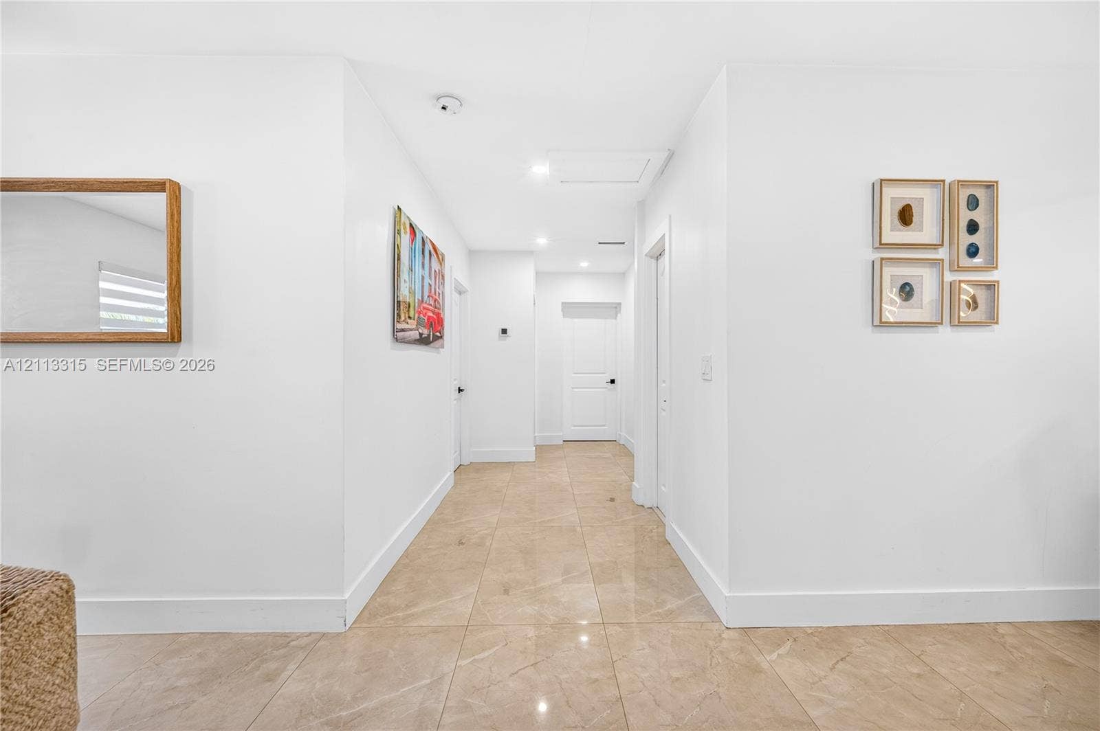 Neutral-toned polished tile flooring, crisp white walls, recessed ceiling lighting, and solid-core interior doors with matte black hardware