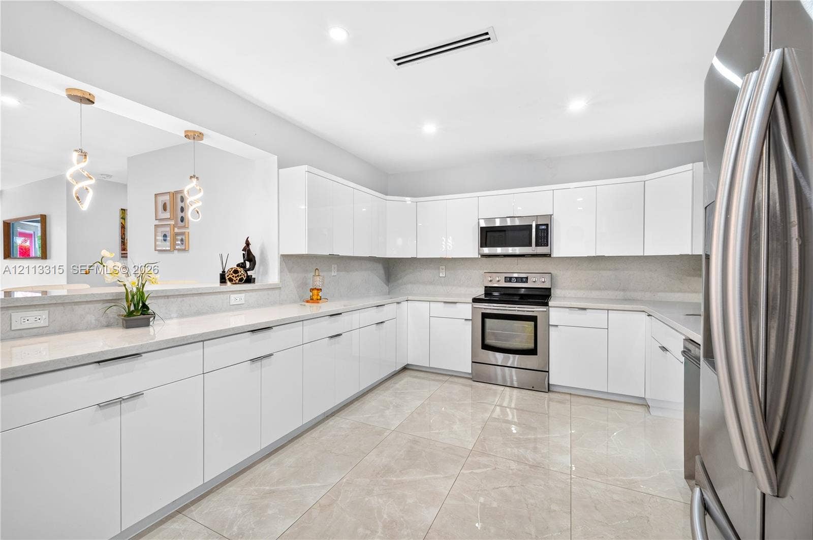 Contemporary kitchen featuring high-gloss white cabinetry, polished stone countertops, stainless steel appliances, large-format tile flooring, and dual modern pendant lighting