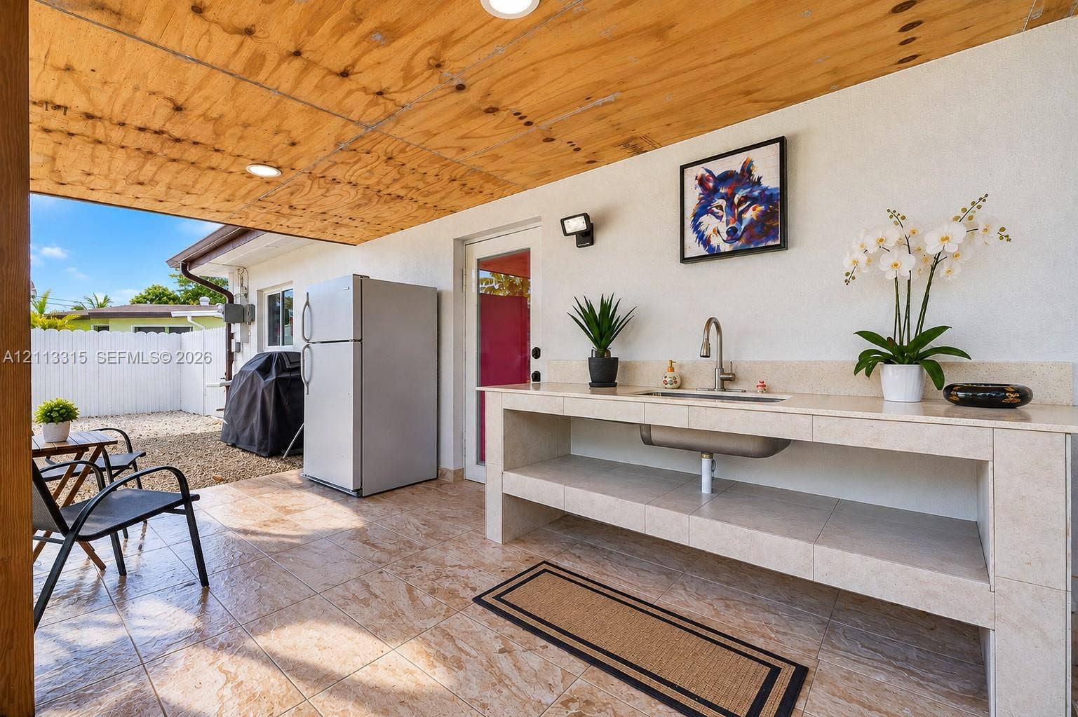 Covered patio featuring a wood-paneled ceiling, tiled flooring, built-in outdoor wet bar with a stone-finish countertop, and recessed lighting