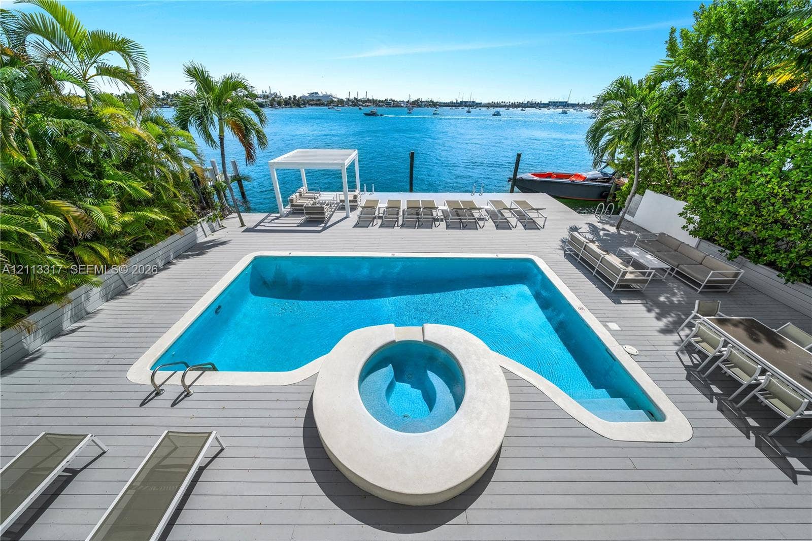 Waterfront deck featuring a swimming pool with a circular spa, a detached covered pavilion, and a private dock