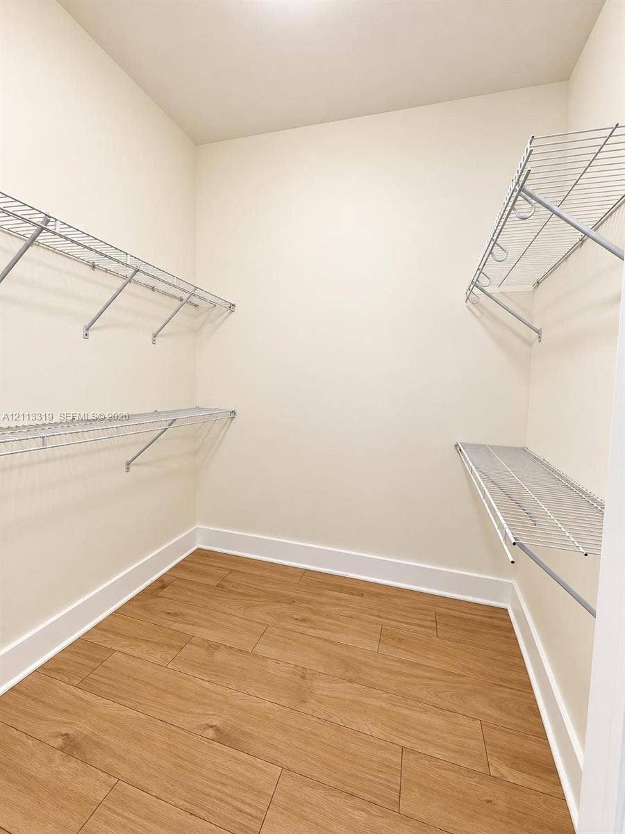 Storage area featuring wood-finish flooring and tiered white wire shelving