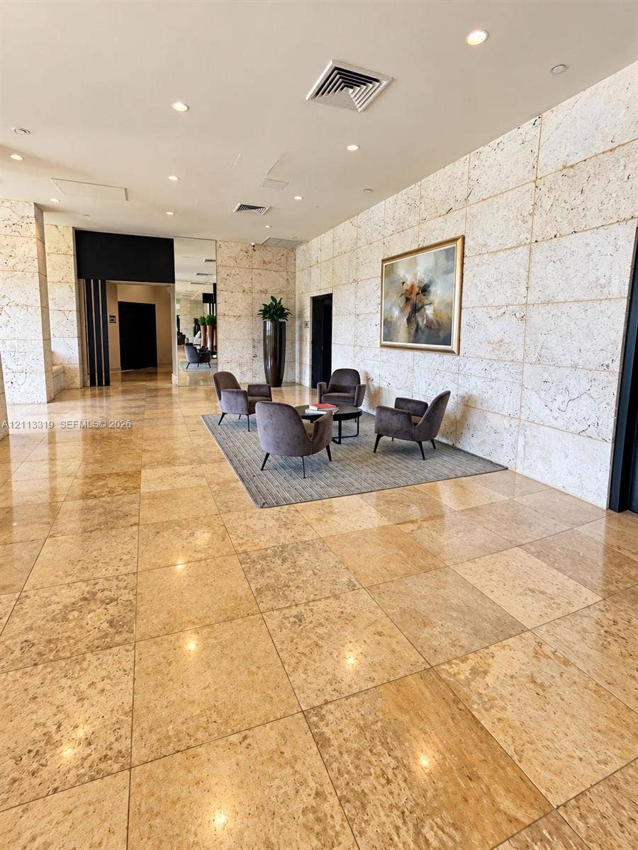 Polished stone flooring, large-scale stone wall cladding, and recessed ceiling lighting