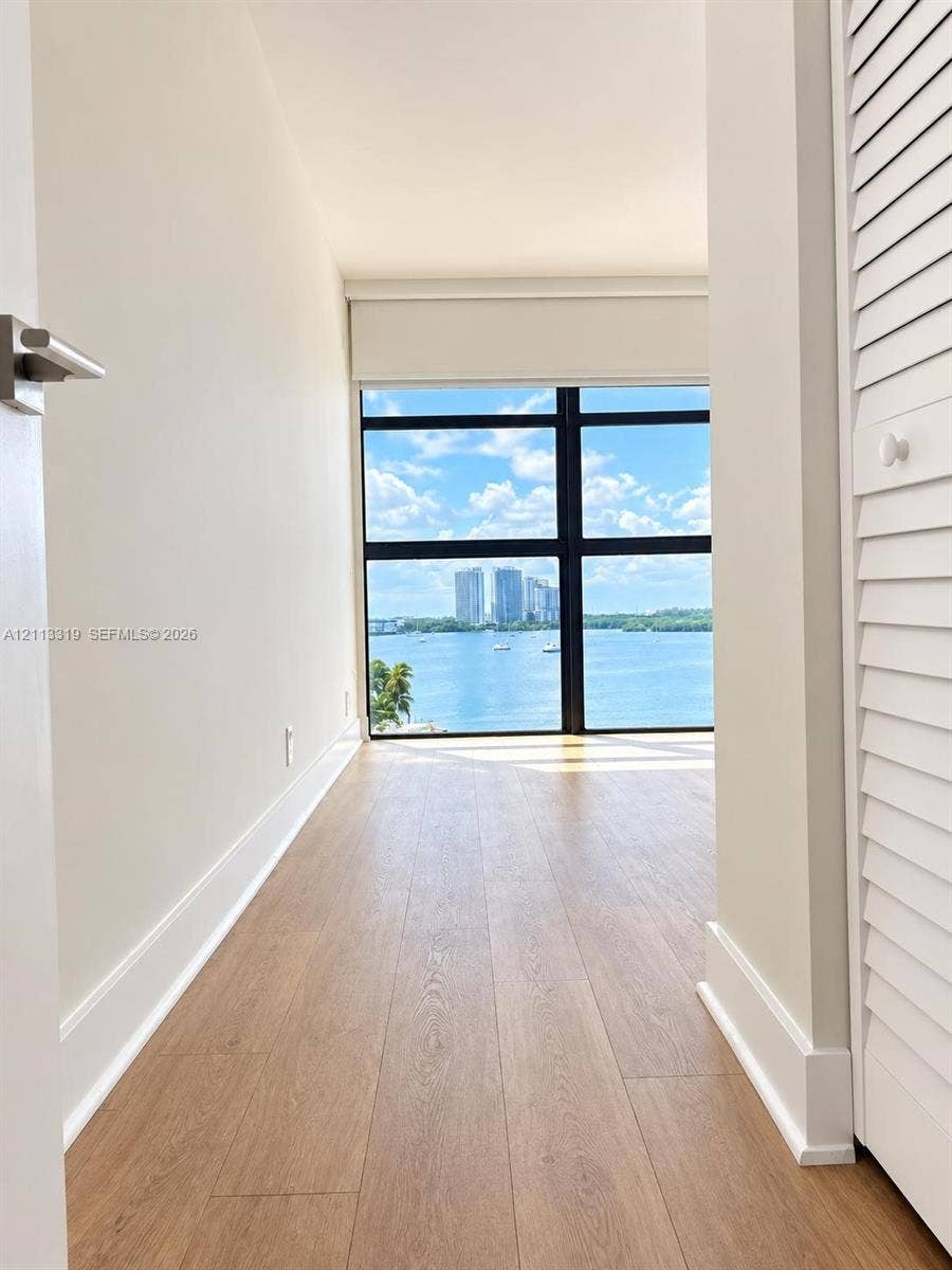 Floor-to-ceiling windows with black framing, wood-finish flooring, and integrated louvered closet doors