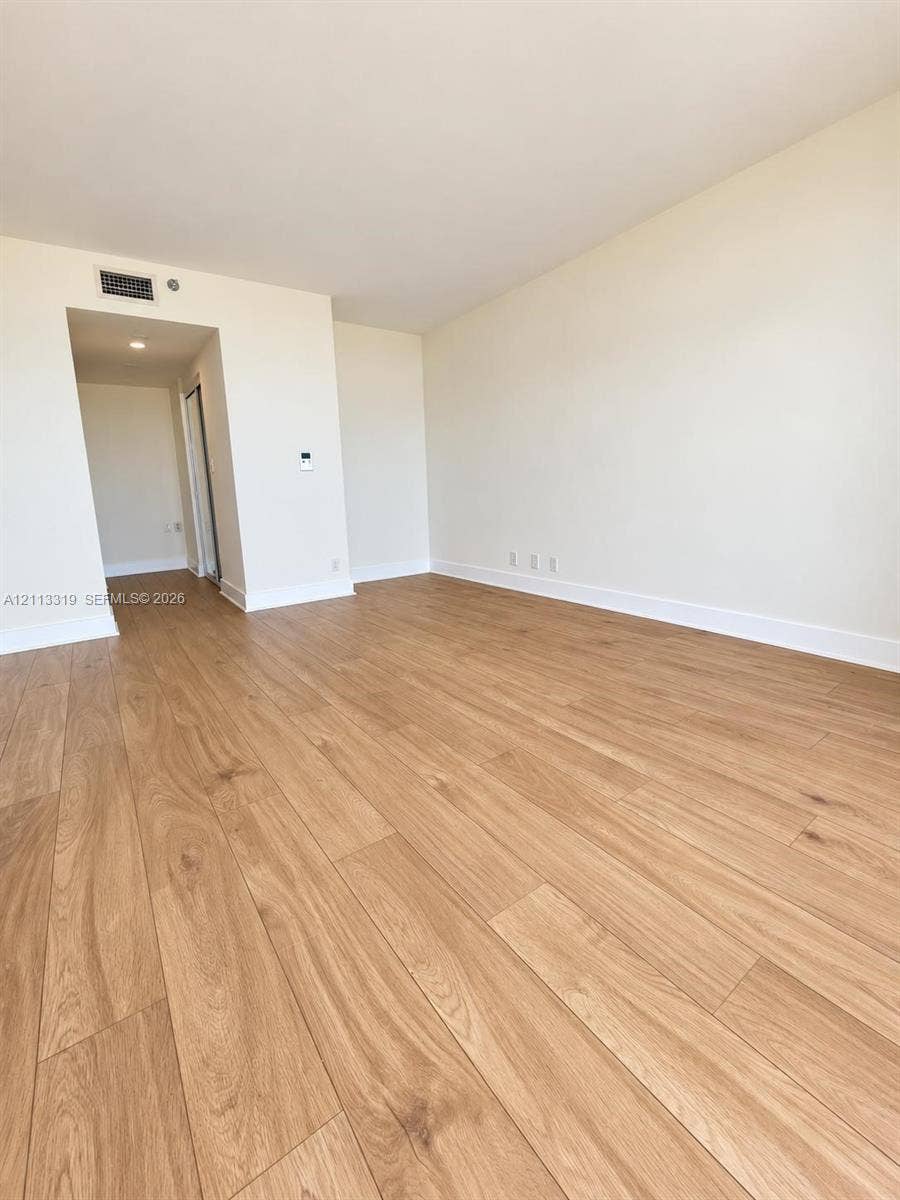 Neutral-toned interior space featuring light wood-finish flooring and recessed ceiling lighting