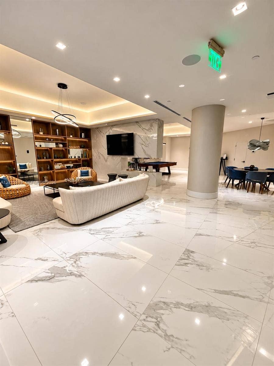 Large-format stone-look tile flooring, custom built-in wood shelving, coffered ceiling with recessed lighting, and a stone-clad feature wall