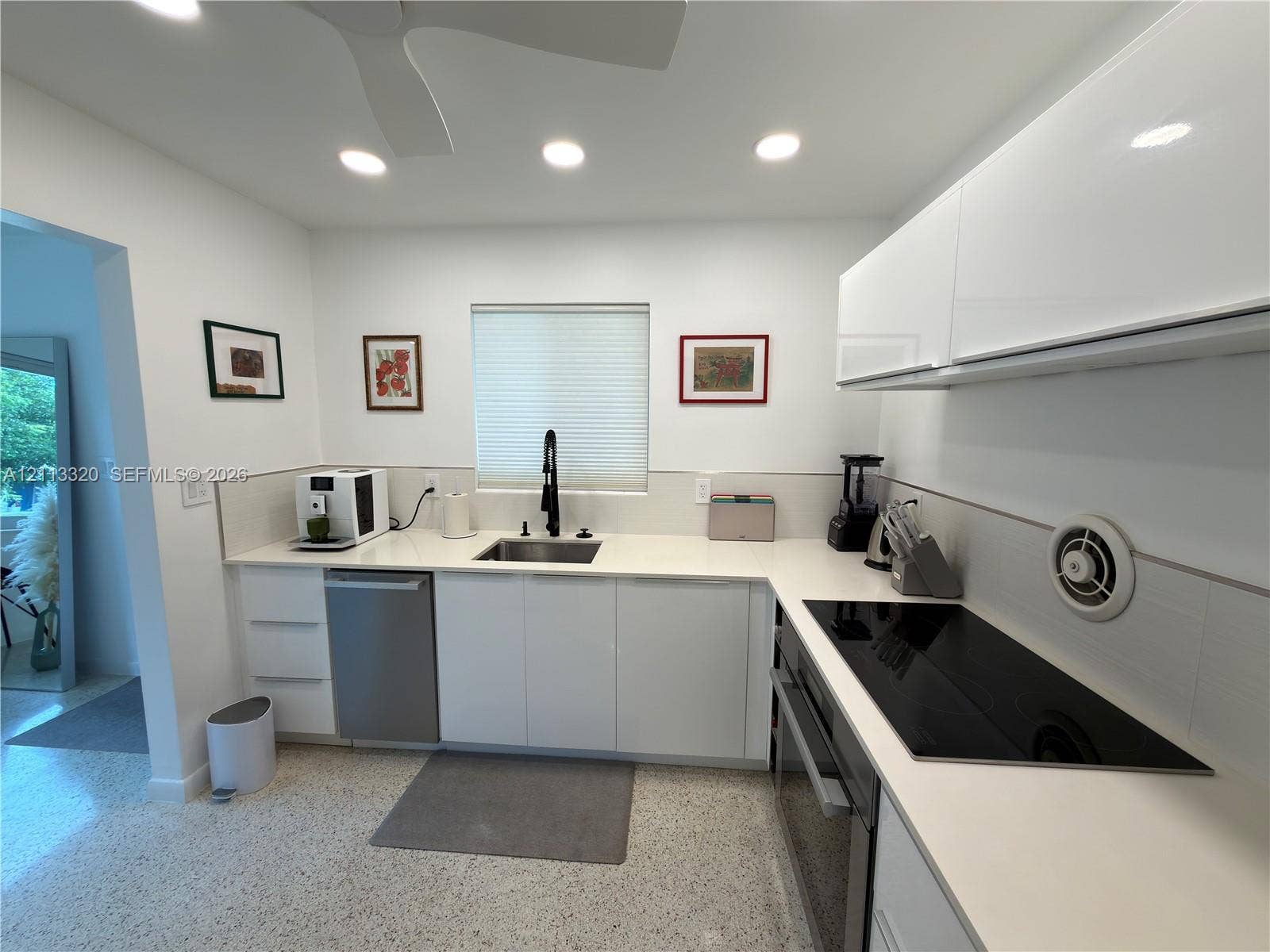 712 NE 25th Avenue, Pompano Beach, FL 33062 Kitchen featuring white high-gloss cabinetry, stone-finish countertops, stainless steel undermount sink with matte black gooseneck faucet, glass cooktop, and polished aggregate flooring
