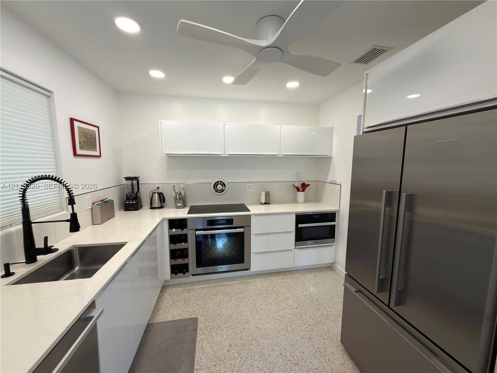 712 NE 25th Avenue, Pompano Beach, FL 33062 Modern kitchen featuring flat-panel white cabinetry, stone-finish countertops, stainless steel appliances, a built-in wine rack, and terrazzo flooring