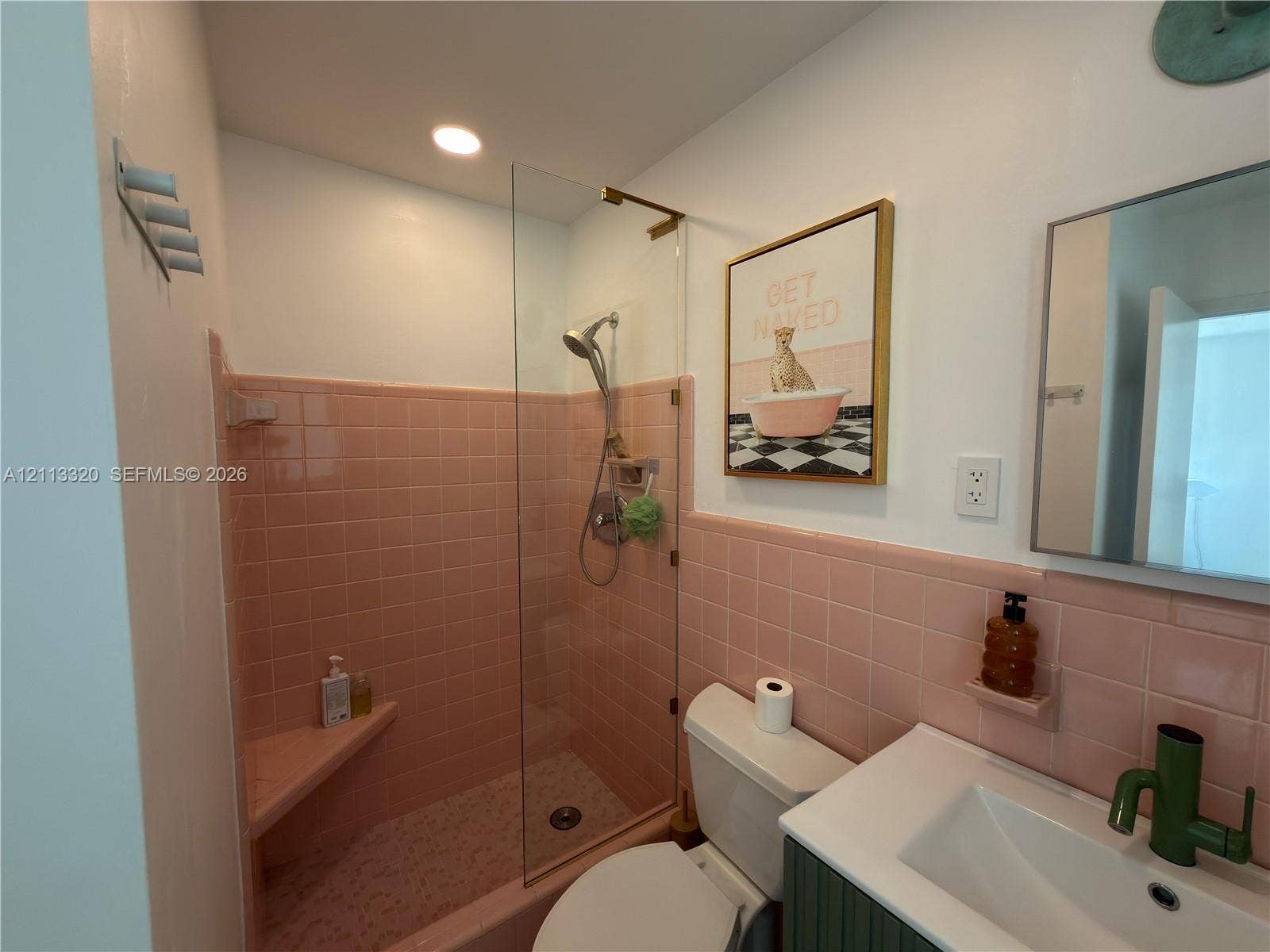 712 NE 25th Avenue, Pompano Beach, FL 33062 Bathroom featuring a glass shower panel, built-in tiled corner bench, handheld showerhead, wall-mounted vanity with a rectangular basin, and decorative tile wall surrounds