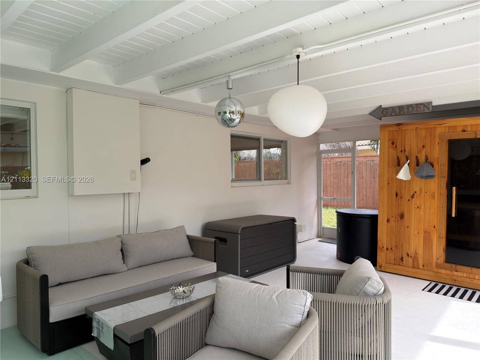 712 NE 25th Avenue, Pompano Beach, FL 33062 Covered patio featuring an exposed-beam ceiling, glass-paneled exterior door, pendant lighting, and a built-in wooden structure