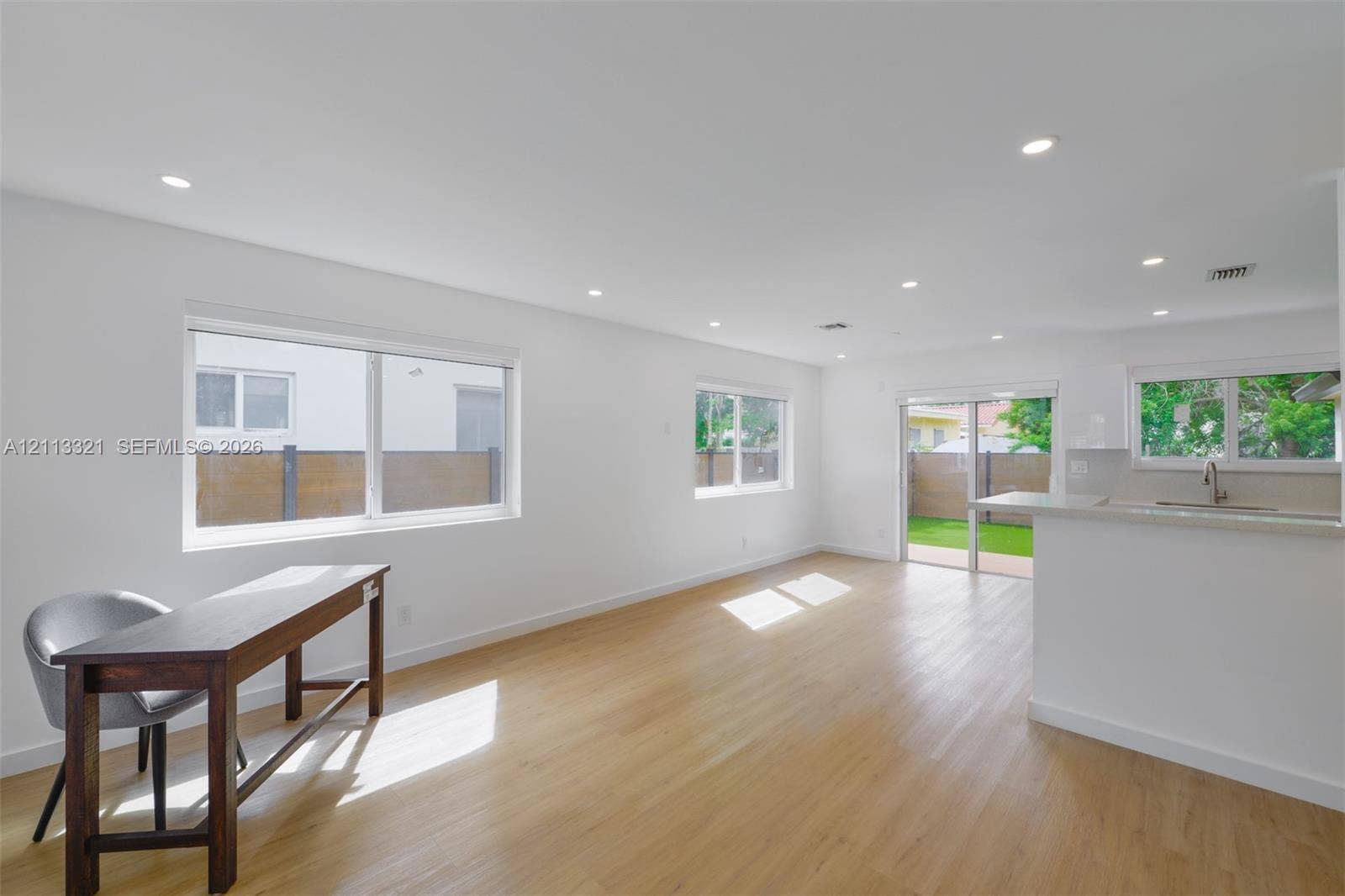Open interior featuring wood-finish flooring, recessed lighting, white cabinetry, a peninsula counter, and sliding glass doors