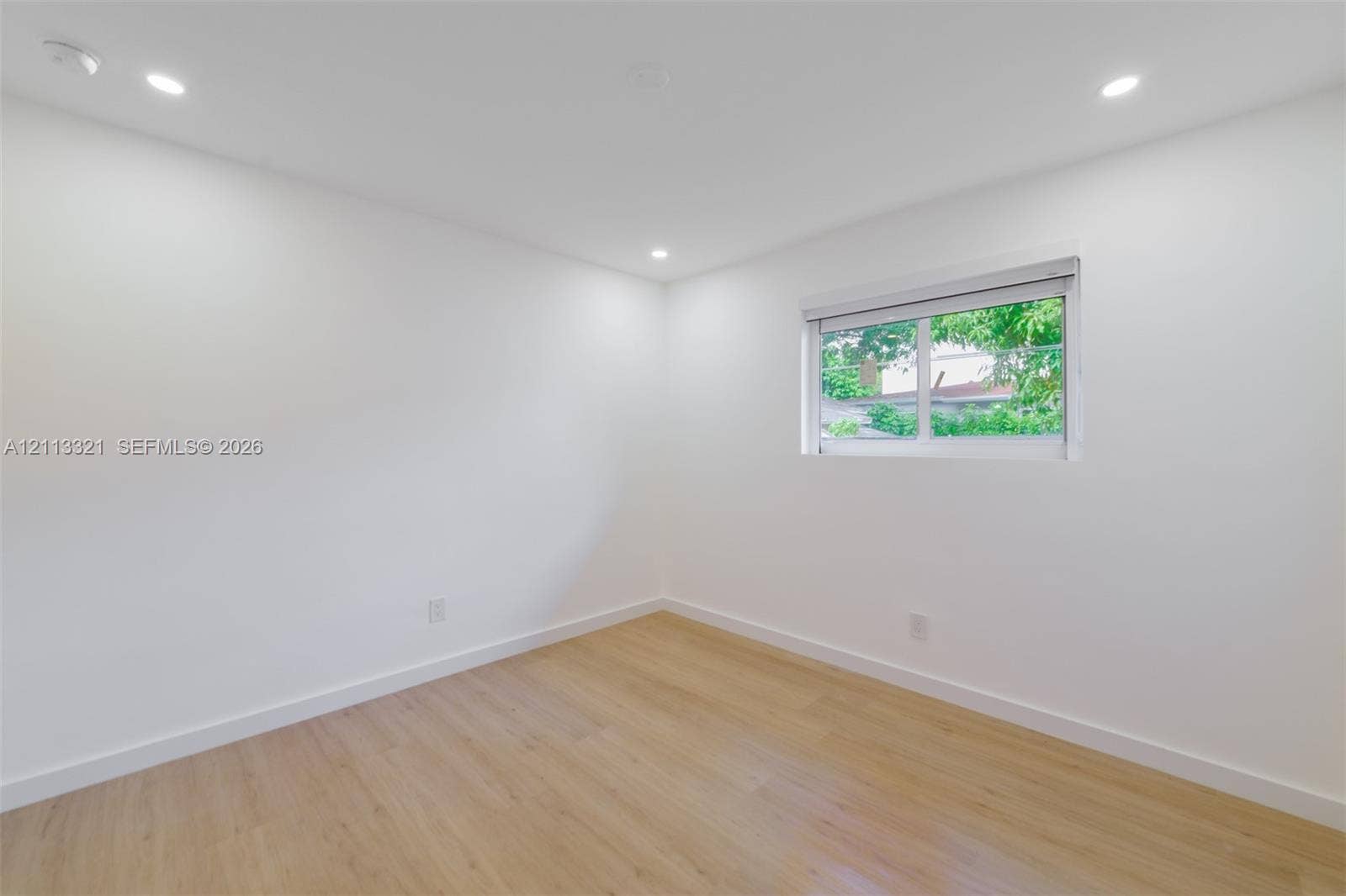 Neutral interior featuring wood-finish flooring, recessed lighting, and a horizontal sliding window