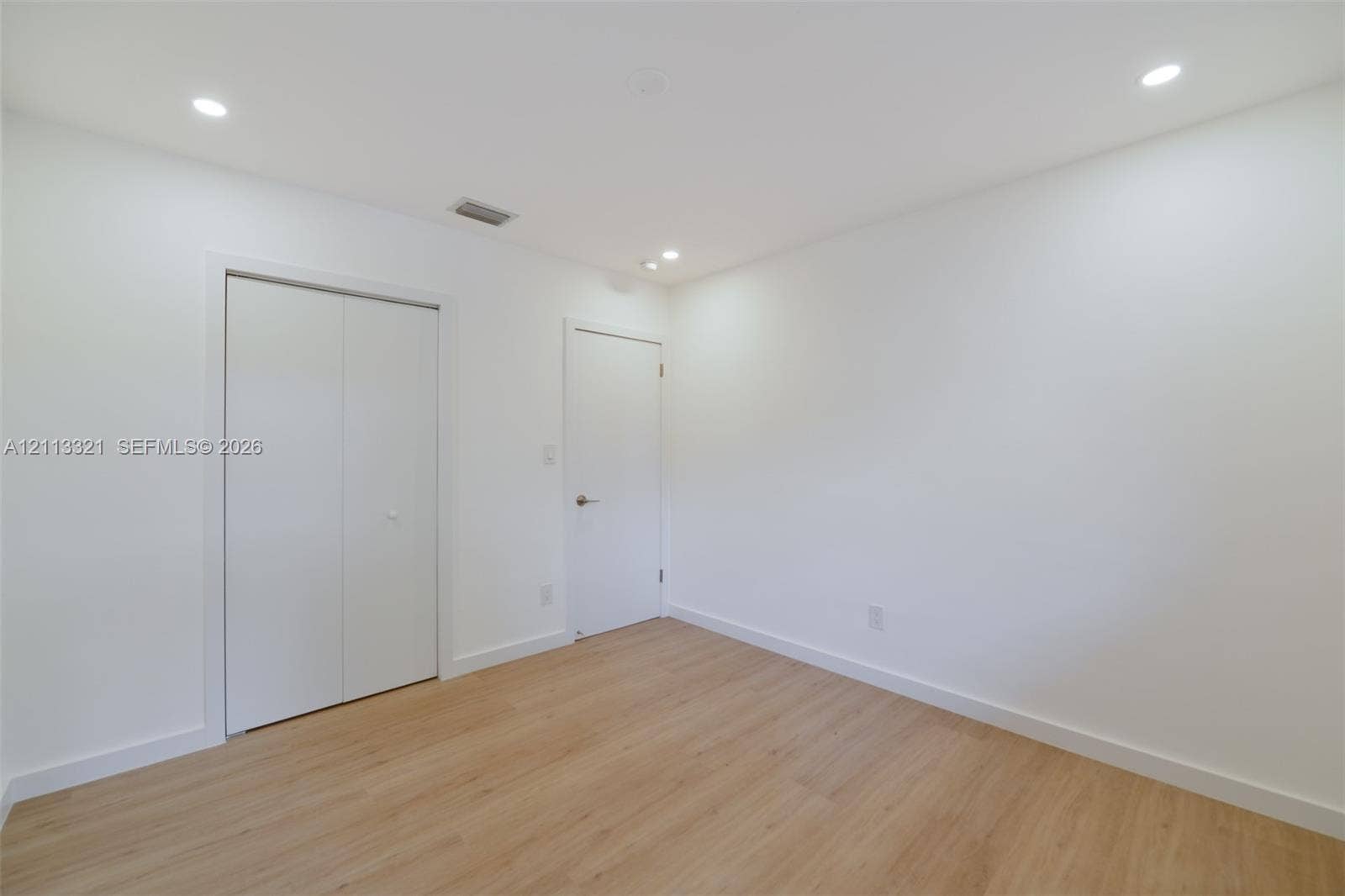 Neutral interior featuring wood-finish flooring, recessed lighting, and white cabinetry doors