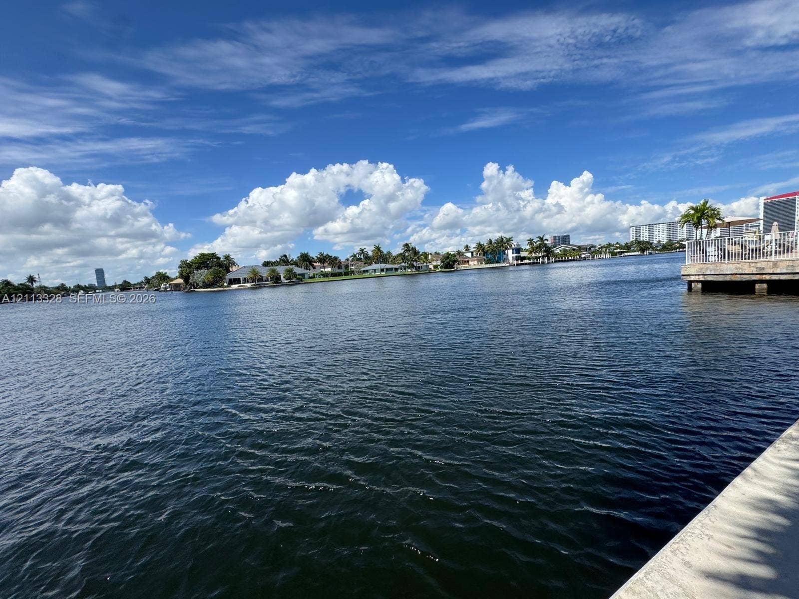 Hallandale Beach, FL 33009 Waterfront property featuring a concrete seawall, metal railing, and paved terrace