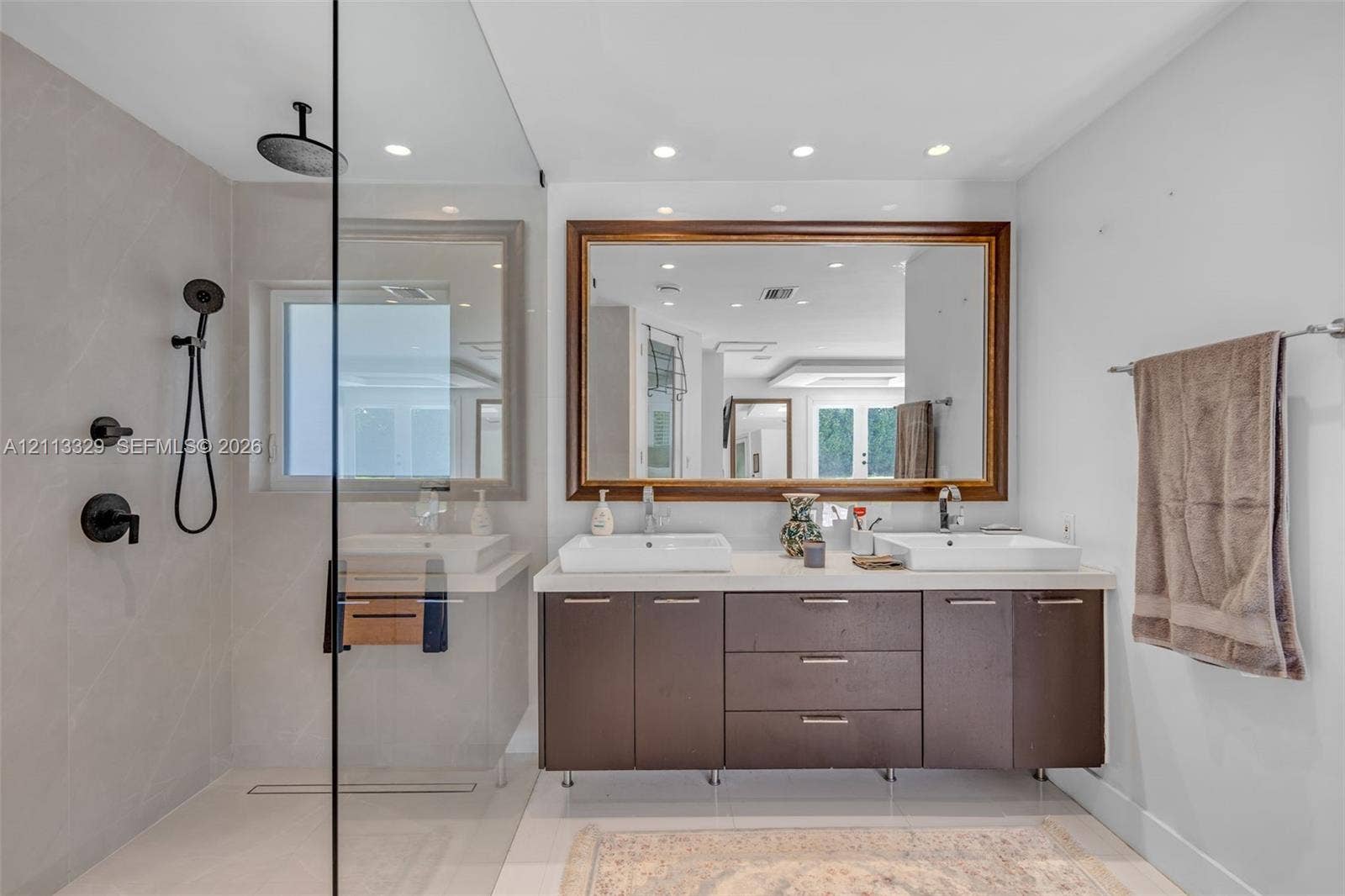 6440 SW 144th Street, Coral Gables, FL 33158 Double vanity with rectangular vessel sinks, quartz countertop, glass-enclosed shower featuring a rainfall showerhead, and a large framed mirror