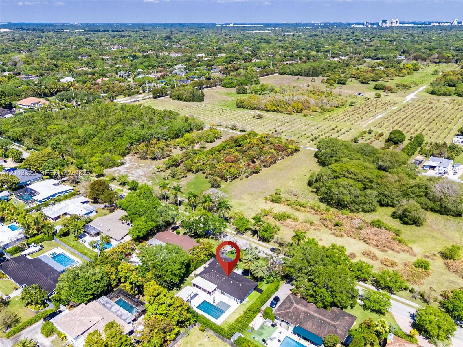 6440 SW 144th Street, Coral Gables, FL 33158 Aerial perspective of a property featuring a private swimming pool, expansive grounds, mature landscaping, and a multi-pitched roofline