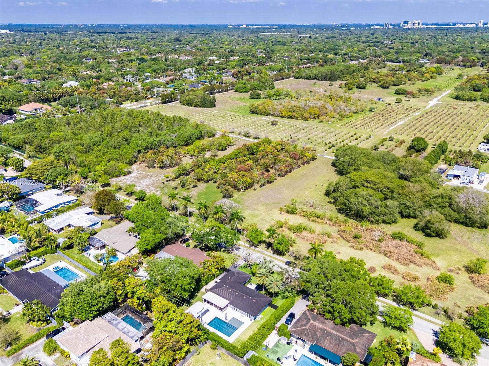 6440 SW 144th Street, Coral Gables, FL 33158 Aerial perspective of expansive residential acreage featuring mature trees, diverse vegetation, and paved access roads