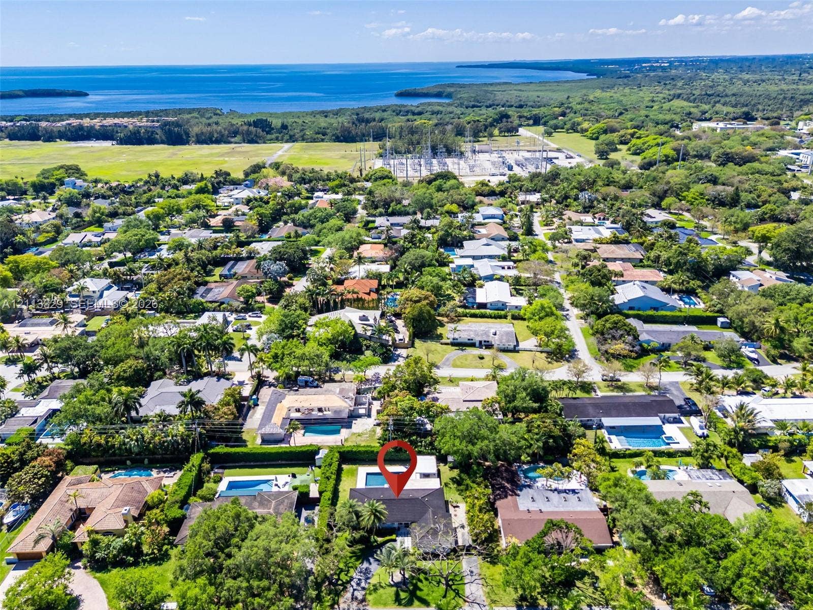6440 SW 144th Street, Coral Gables, FL 33158 Aerial perspective showcasing a residential property with a swimming pool and mature landscaping, positioned within a coastal environment