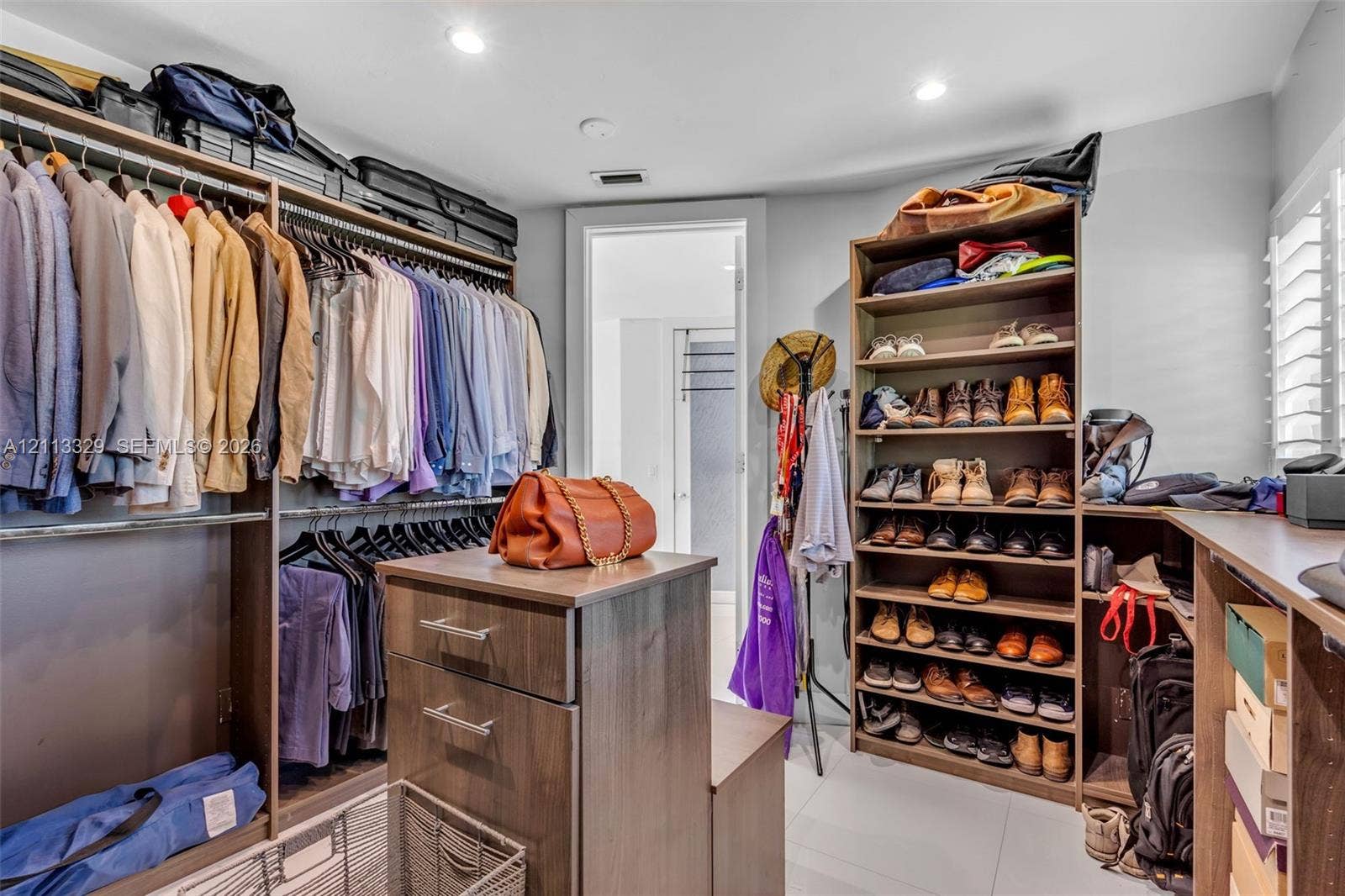 6440 SW 144th Street, Coral Gables, FL 33158 Walk-in storage space featuring built-in wood-finish shelving, an integrated center island with drawers, double-tier clothing rods, and recessed lighting