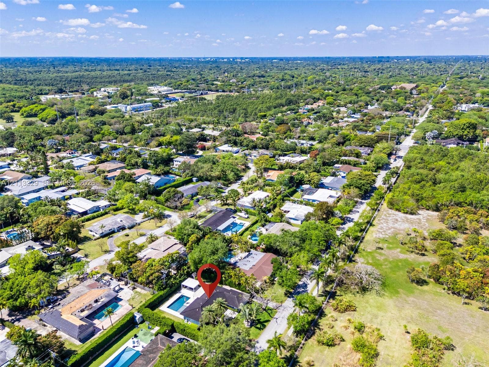 6440 SW 144th Street, Coral Gables, FL 33158 Aerial perspective of a property featuring a swimming pool, covered outdoor area, mature perimeter landscaping, and shingle-style roof