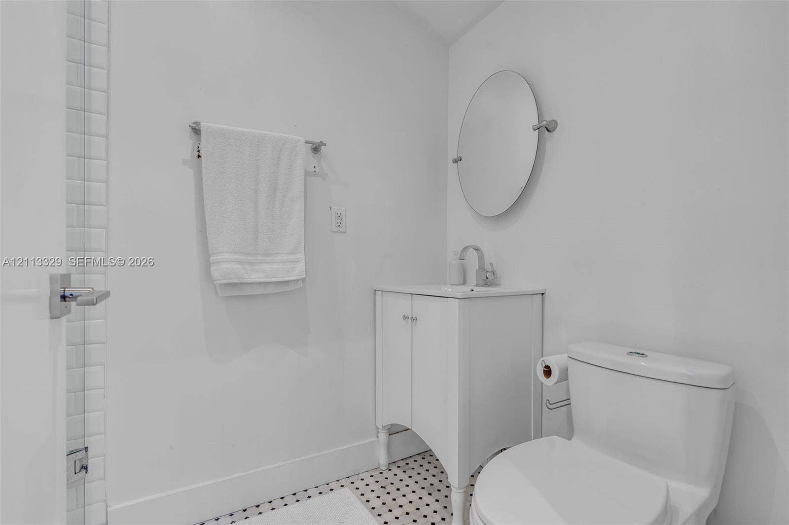 6440 SW 144th Street, Coral Gables, FL 33158 White vanity with a square sink, chrome faucet, oval wall-mounted mirror, and black-and-white mosaic tile flooring