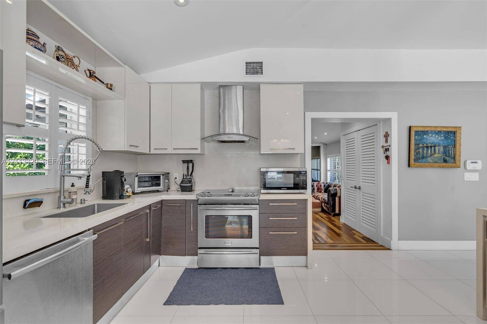 6440 SW 144th Street, Coral Gables, FL 33158 Kitchen featuring two-tone flat-panel cabinetry, quartz countertops, stainless steel appliances, a professional-style pull-down faucet, and polished tile flooring