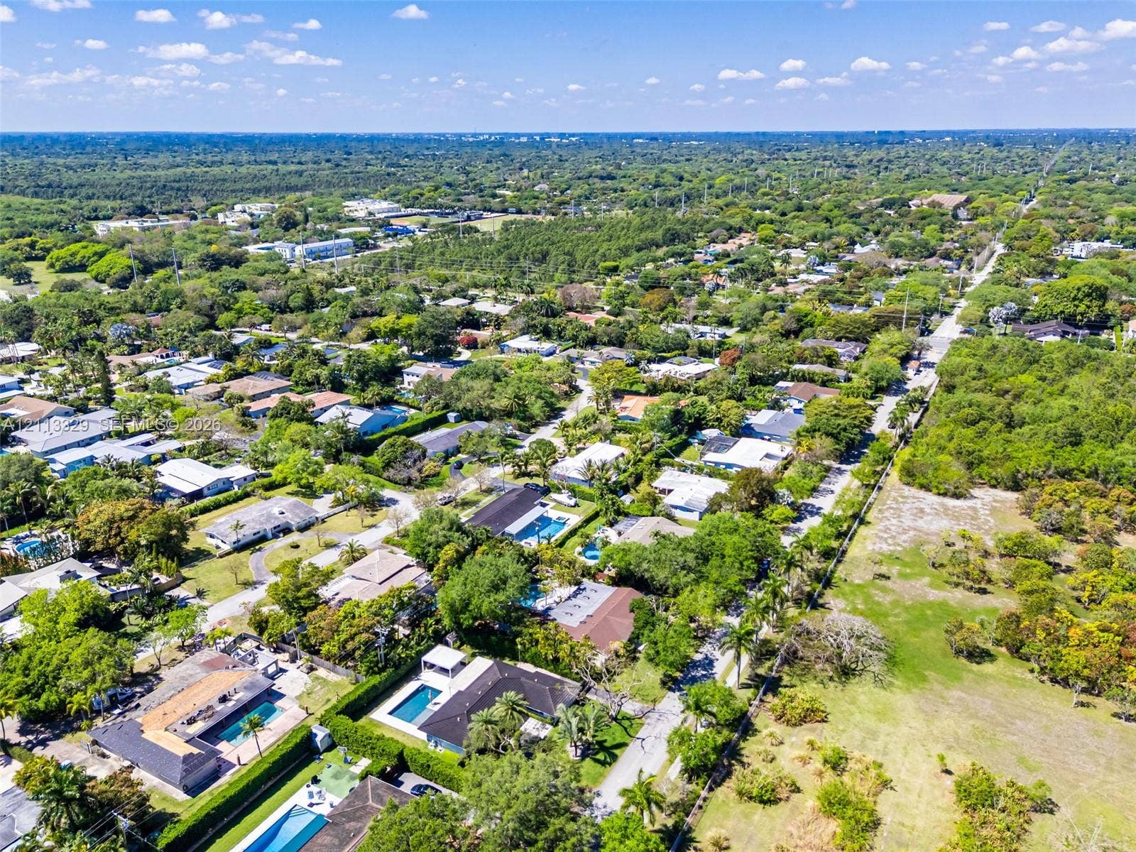 6440 SW 144th Street, Coral Gables, FL 33158 Aerial perspective of the residential grounds featuring mature canopy trees, structured paved street access, and expansive green space