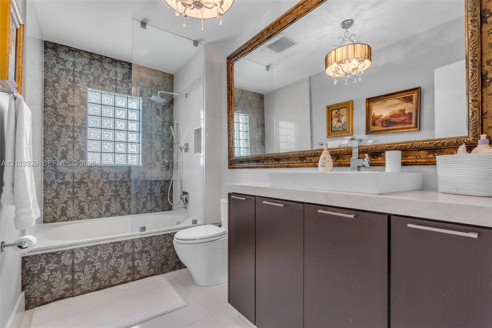 6440 SW 144th Street, Coral Gables, FL 33158 Bathroom featuring a floating vanity with a vessel sink, stone-finish countertop, glass-enclosed shower with a glass block window, and large-format tile surround