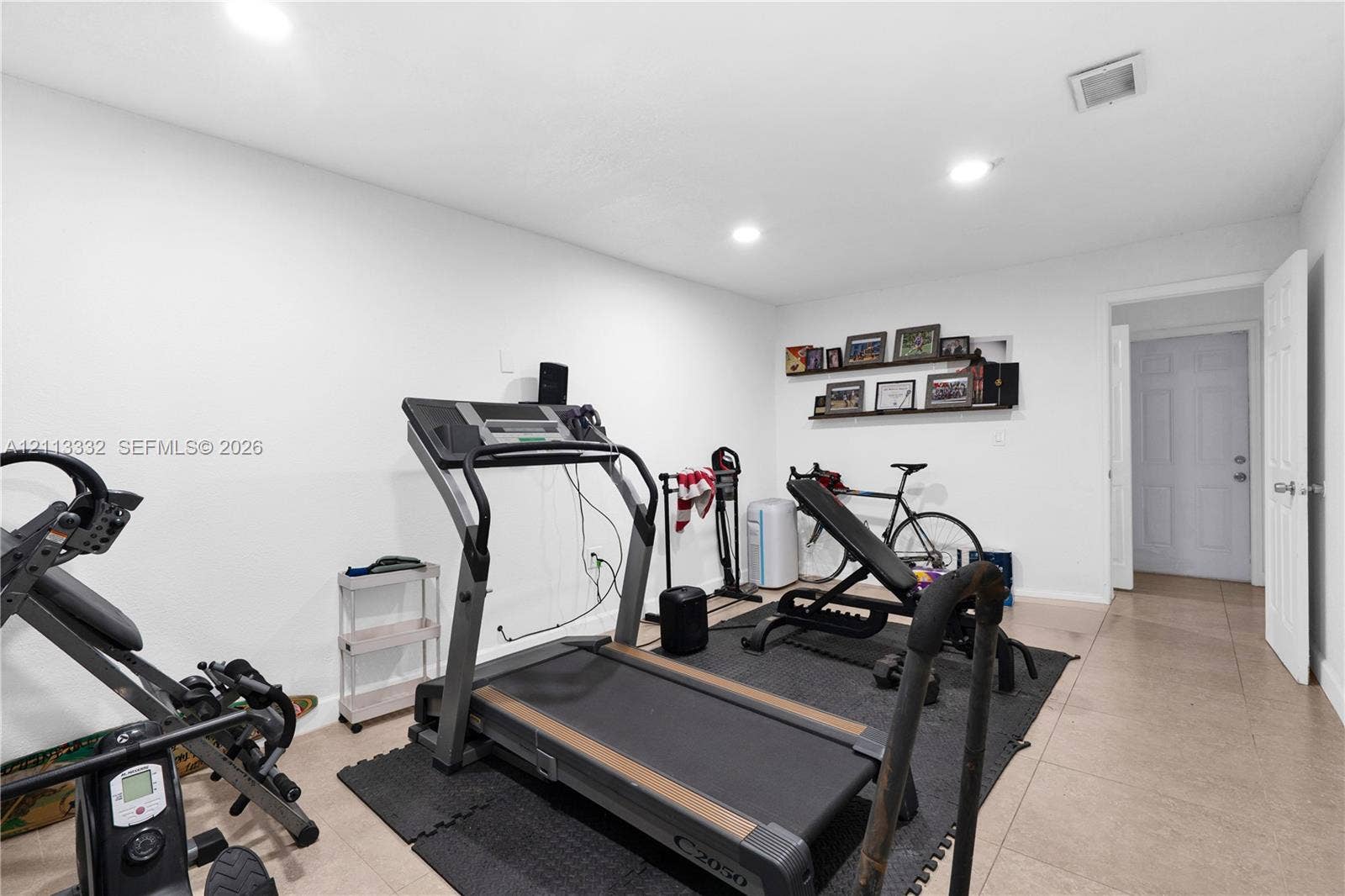 13111 SW 84th Street, Miami, FL 33183 Neutral interior space featuring large-format ceramic tile flooring, recessed ceiling lighting, a built-in wall niche with shelving, and a six-panel interior door