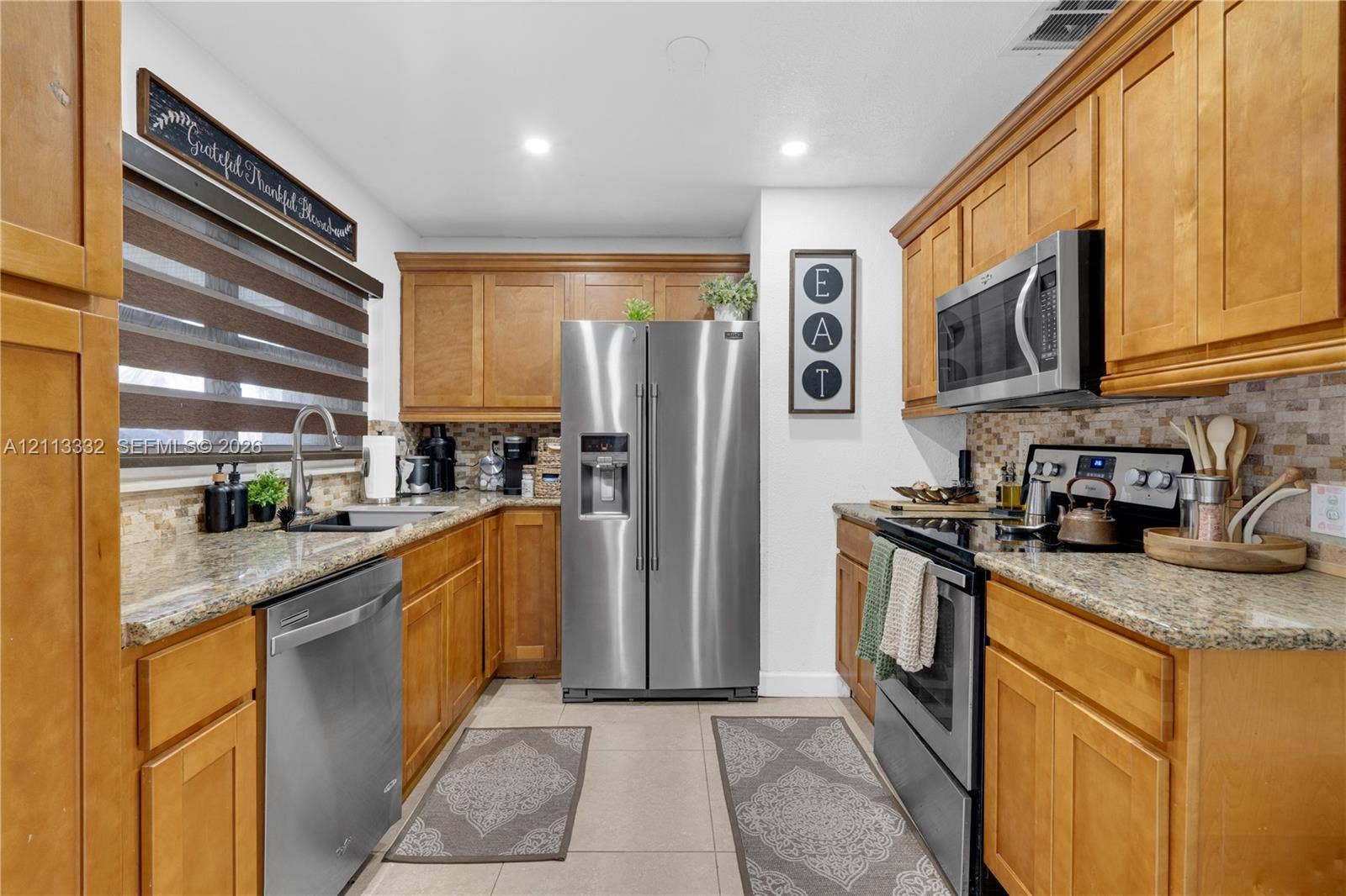 13111 SW 84th Street, Miami, FL 33183 Kitchen featuring honey-toned wood cabinetry, stone countertops, mosaic tile backsplash, stainless steel appliances, and recessed lighting