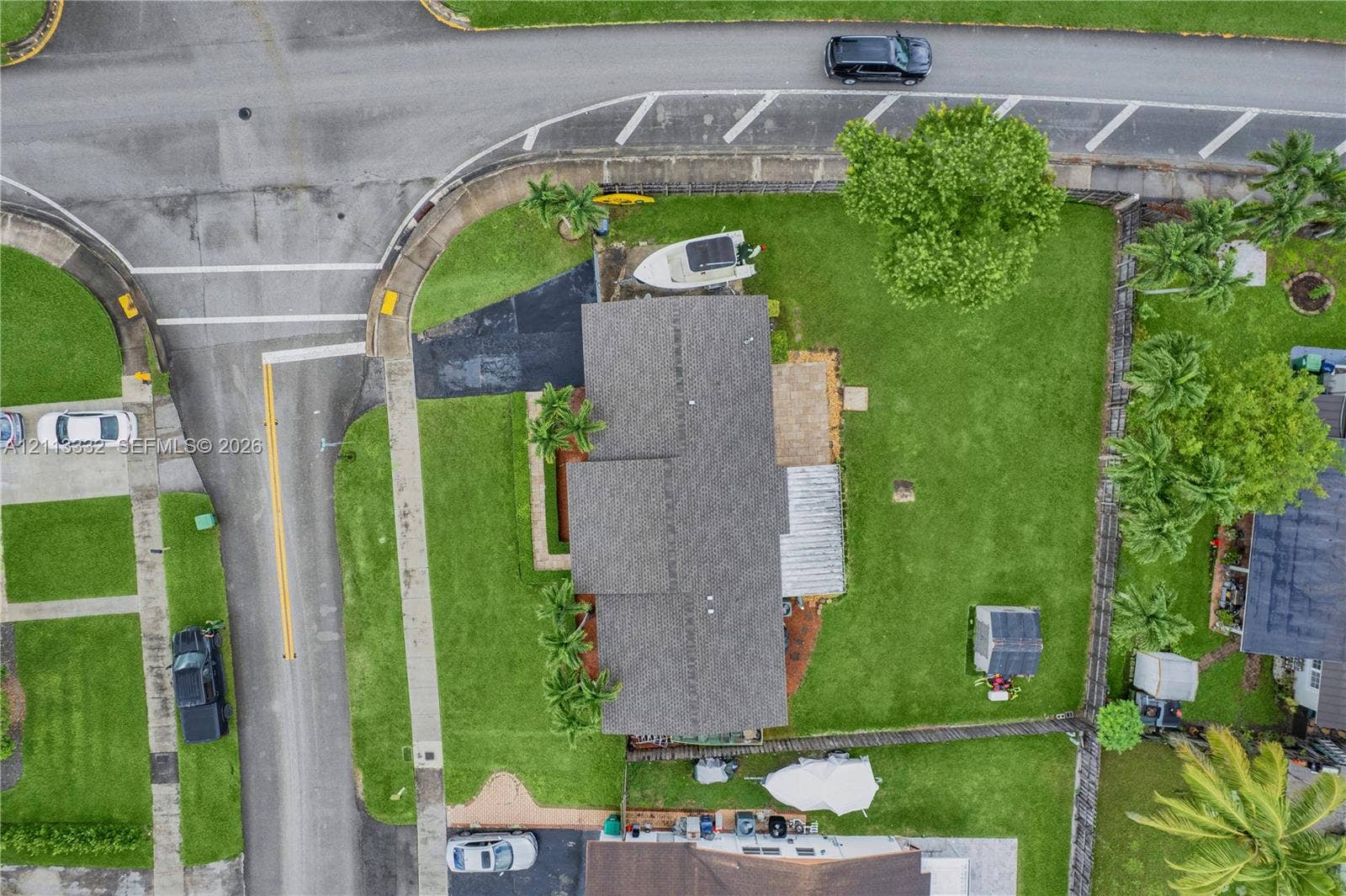 13111 SW 84th Street, Miami, FL 33183 Aerial perspective of a property featuring an asphalt driveway, a paved patio area, a fenced-in lawn, and mature landscaping