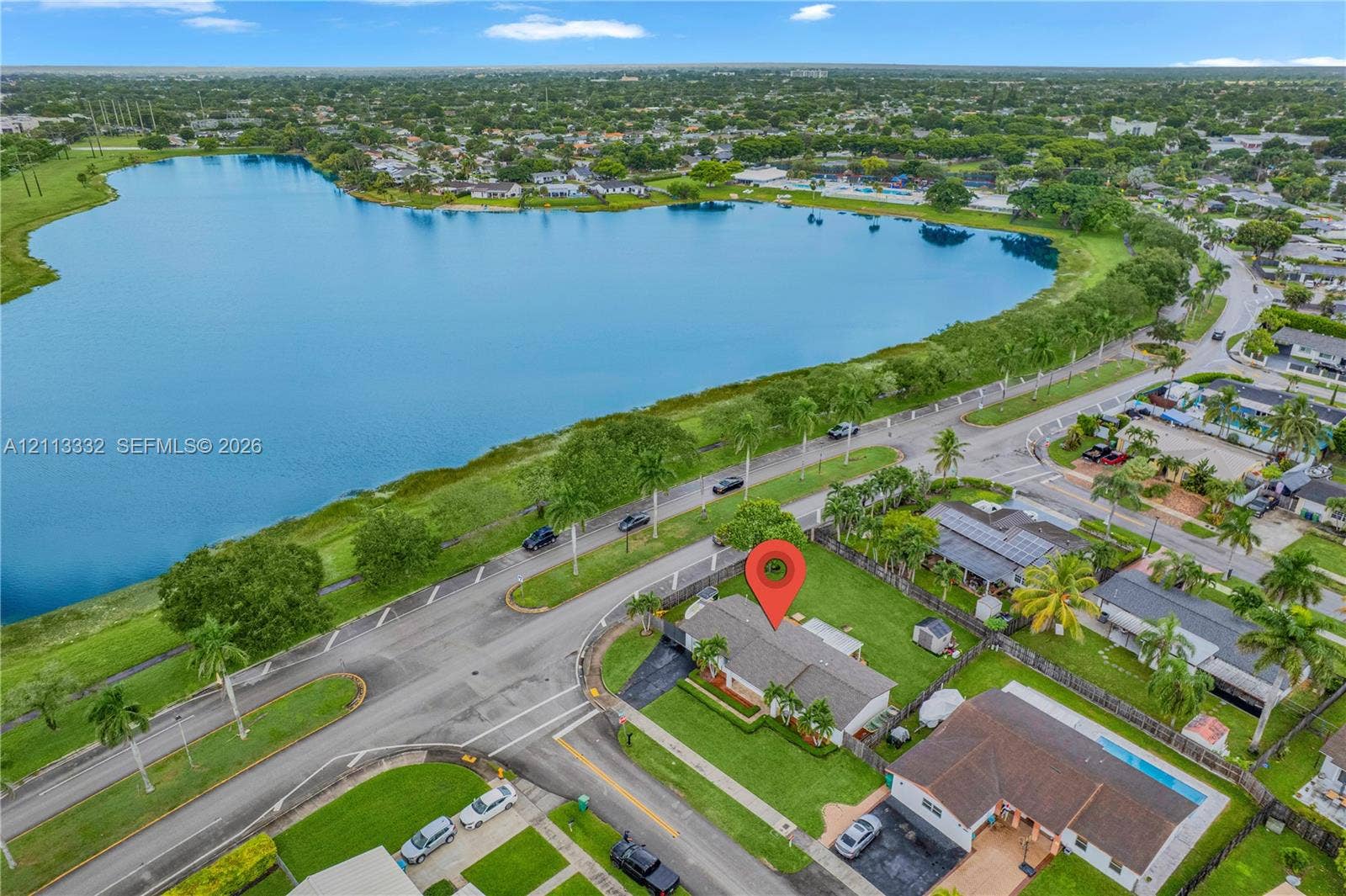 13111 SW 84th Street, Miami, FL 33183 Aerial perspective of residential property featuring a pitched roof, asphalt driveway, and manicured lawn, situated in proximity to a large waterfront