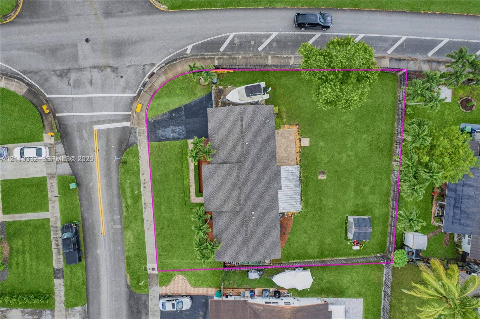 13111 SW 84th Street, Miami, FL 33183 Corner lot featuring a large lawn, paved driveway, stone patio, and detached storage structure