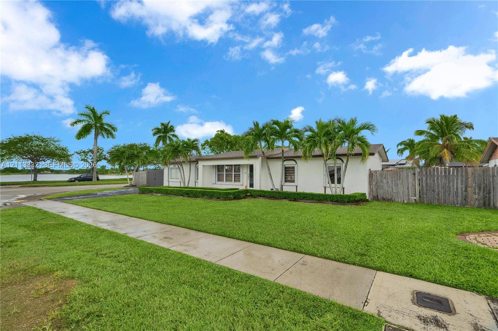 13111 SW 84th Street, Miami, FL 33183 Single-story residence featuring a smooth stucco exterior, manicured lawn, established landscaping, and a wood privacy fence