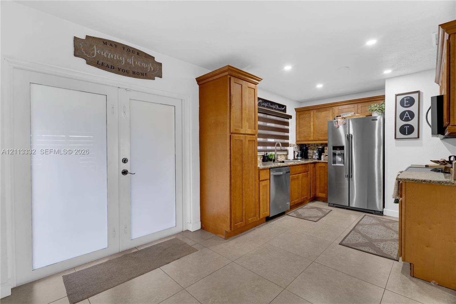 13111 SW 84th Street, Miami, FL 33183 Kitchen featuring shaker-style cabinetry, stainless steel appliances, stone-surface countertops, tile flooring, and dual glass-panel entry doors