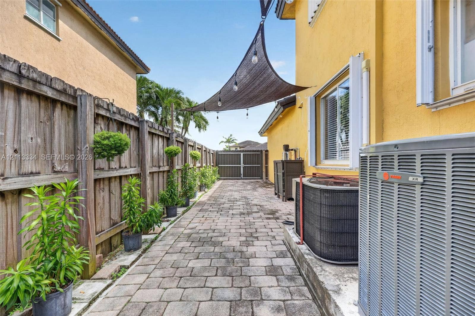 28232 SW 128th Path, Homestead, FL 33033 Side yard featuring paver flooring, wood-panel fencing, and a retractable overhead sun shade