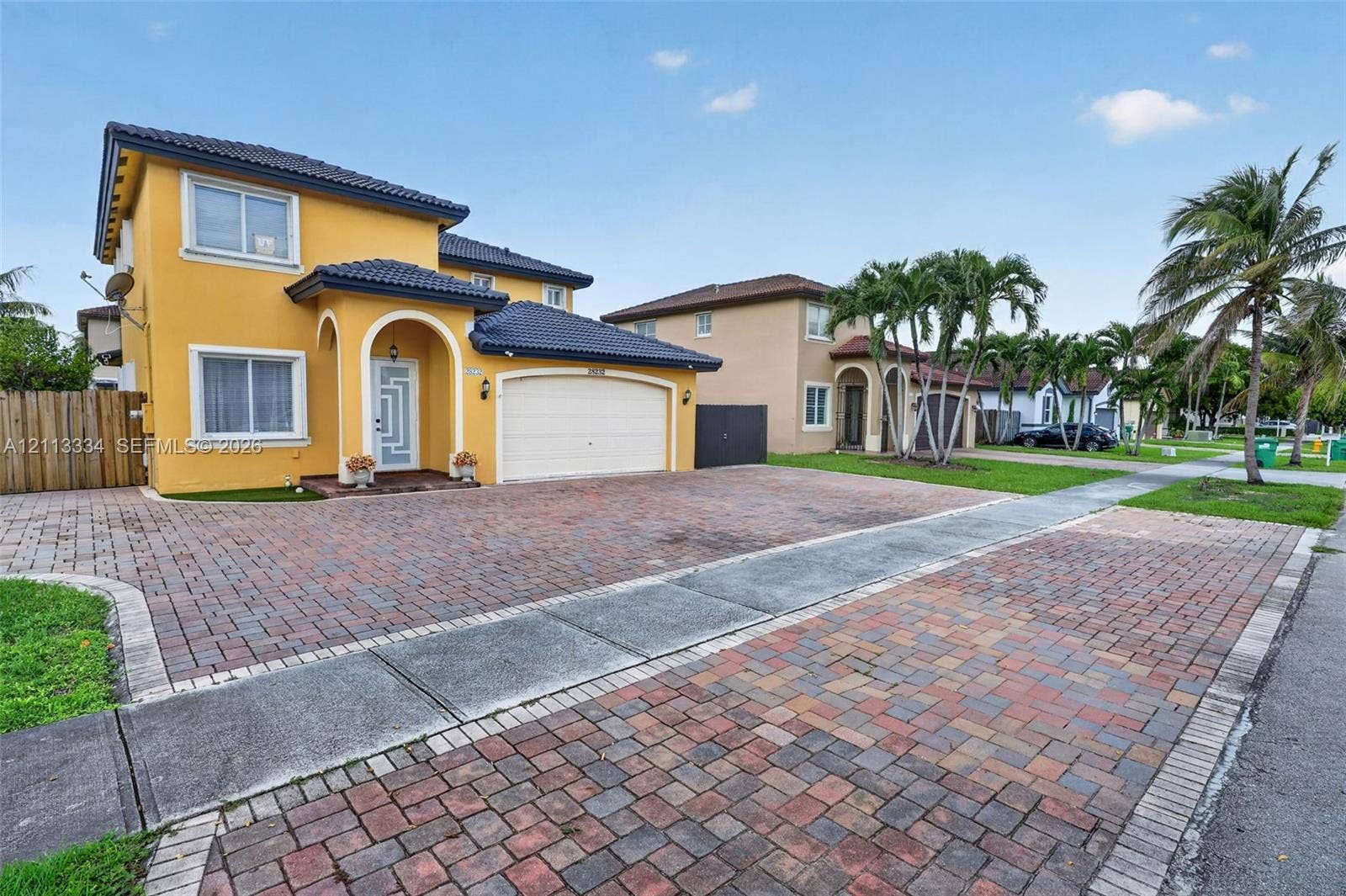 28232 SW 128th Path, Homestead, FL 33033 Two-story residence featuring a tile roof, decorative arched entryway, and extensive paver driveway
