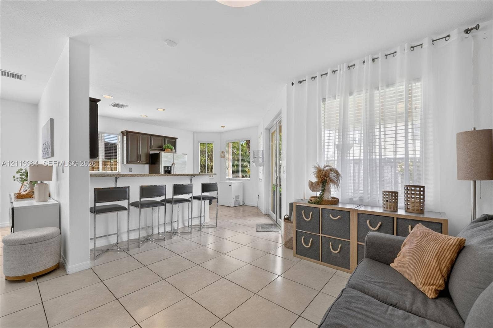 28232 SW 128th Path, Homestead, FL 33033 Open-concept interior featuring light-toned tile flooring, recessed lighting, a kitchen breakfast bar, and glass-paned sliding doors